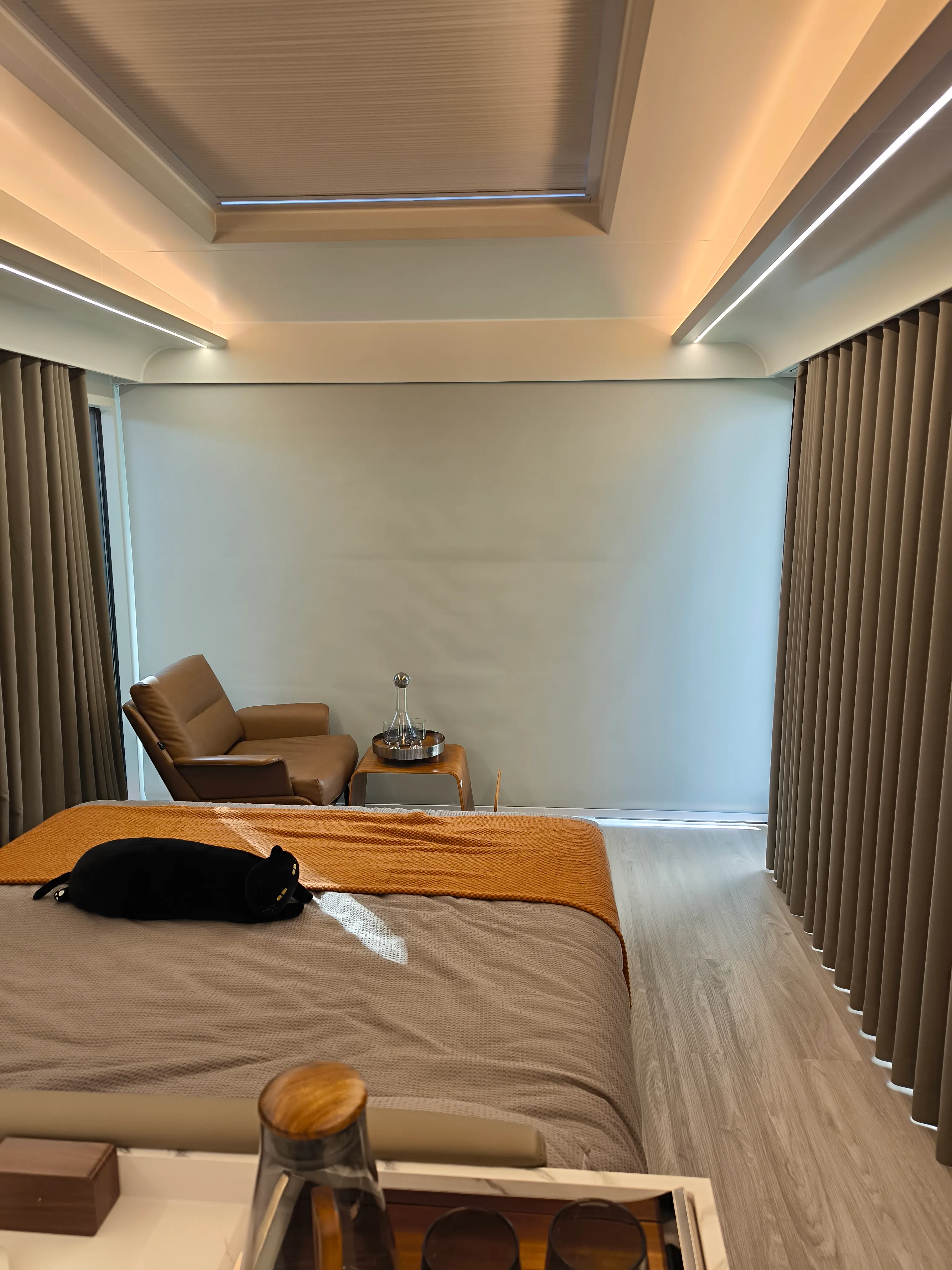 Schlafbereich mit Doppelbett, Vorhängen, Sessel und umlaufender Lichtlinie