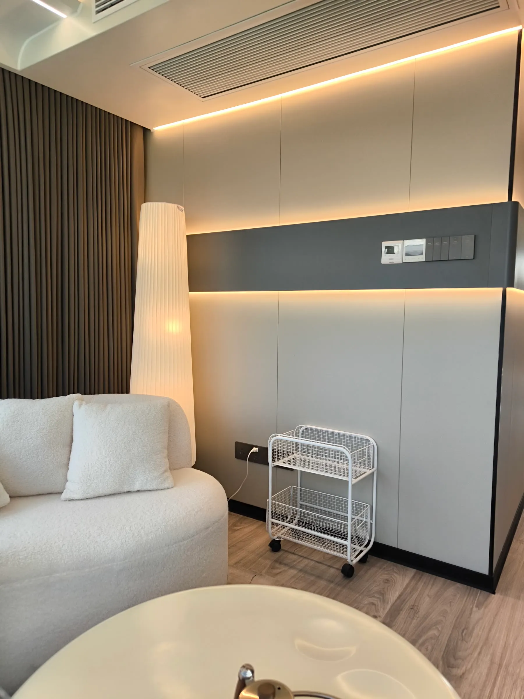 Wohnbereich mit Sofa, Tisch und indirekt beleuchteter Wandfläche